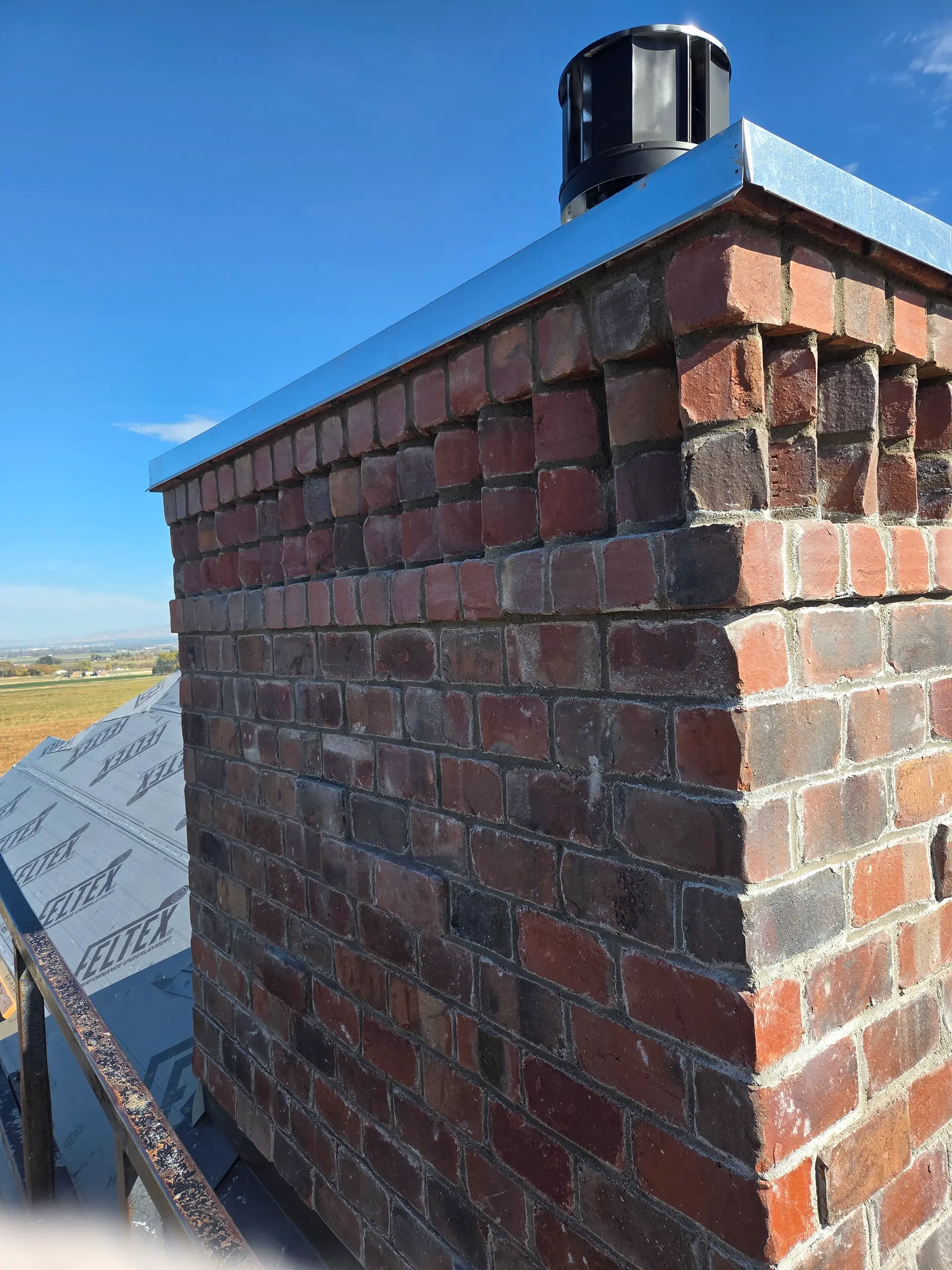 Restored brick chimney with new metal cap by Spackman Construction Services in northern Utah