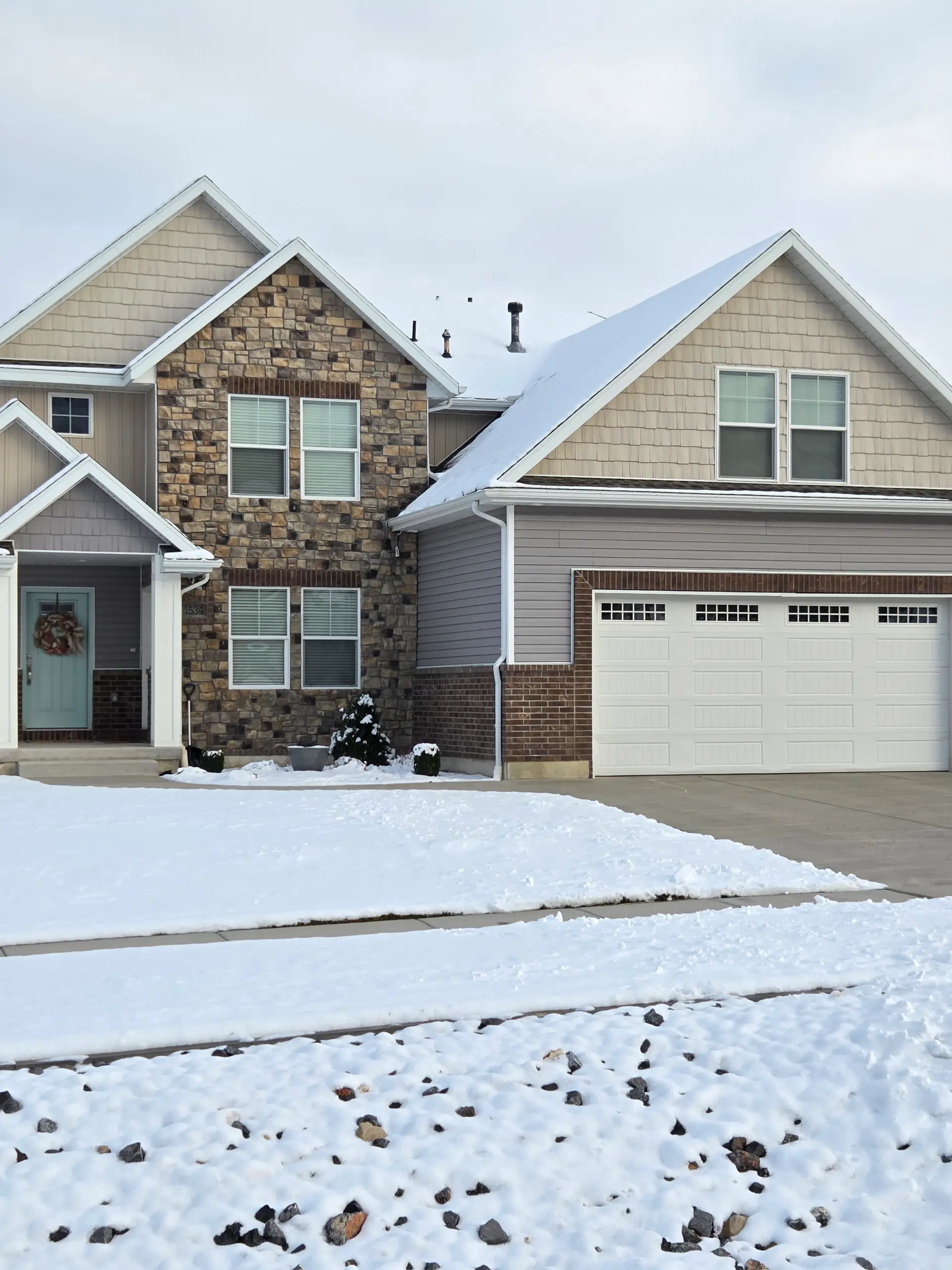 Residential driveway and concrete walkway leading to a stone-veneer entry by Spackman Construction Services