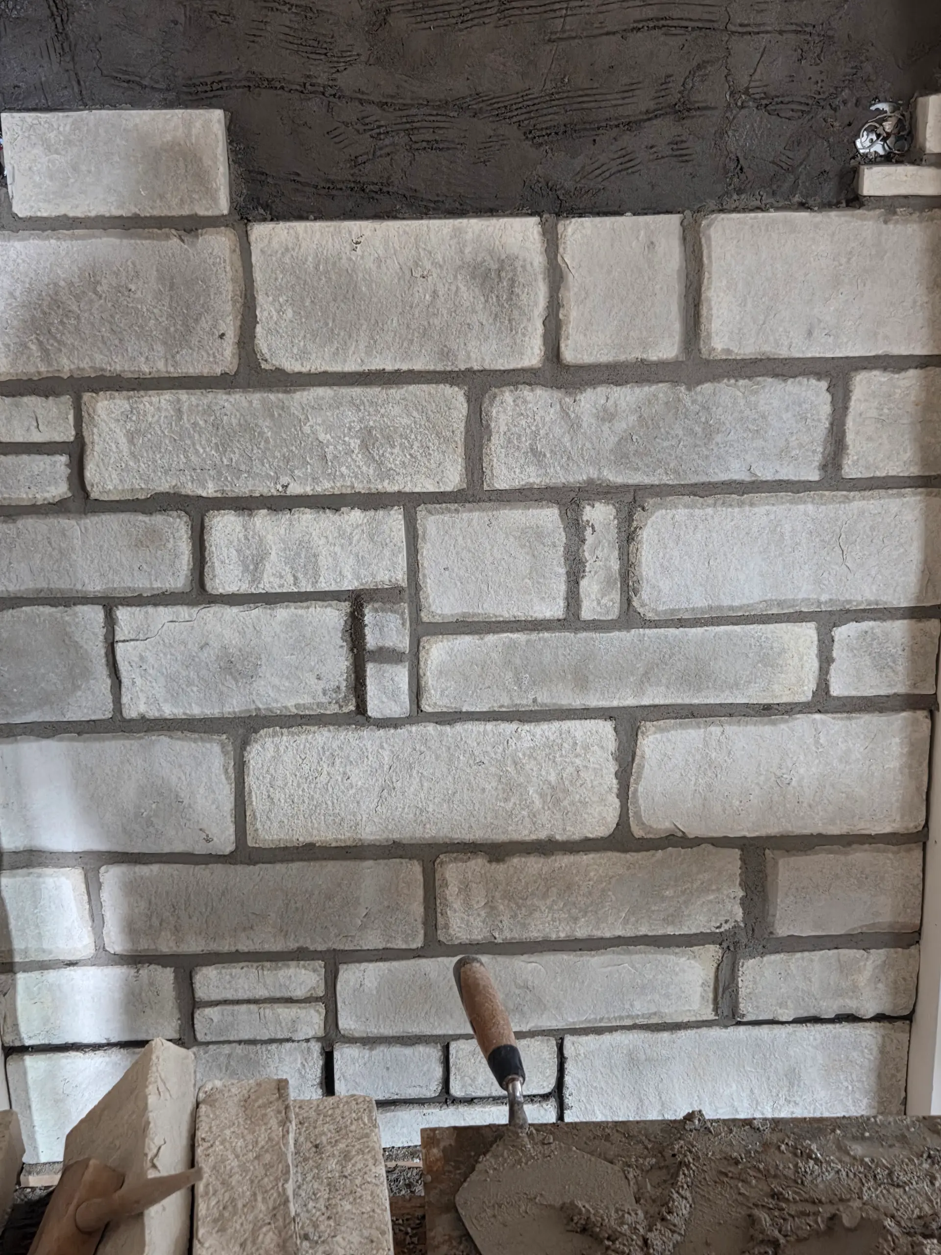 In-progress limestone rock veneer installation with trowel and mortar by Spackman Construction Services